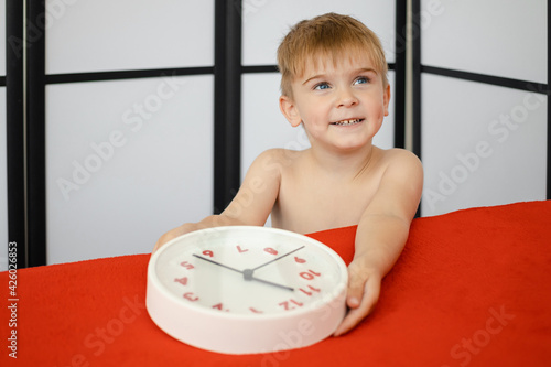 cheerful little boy holding a watch and examining the dial