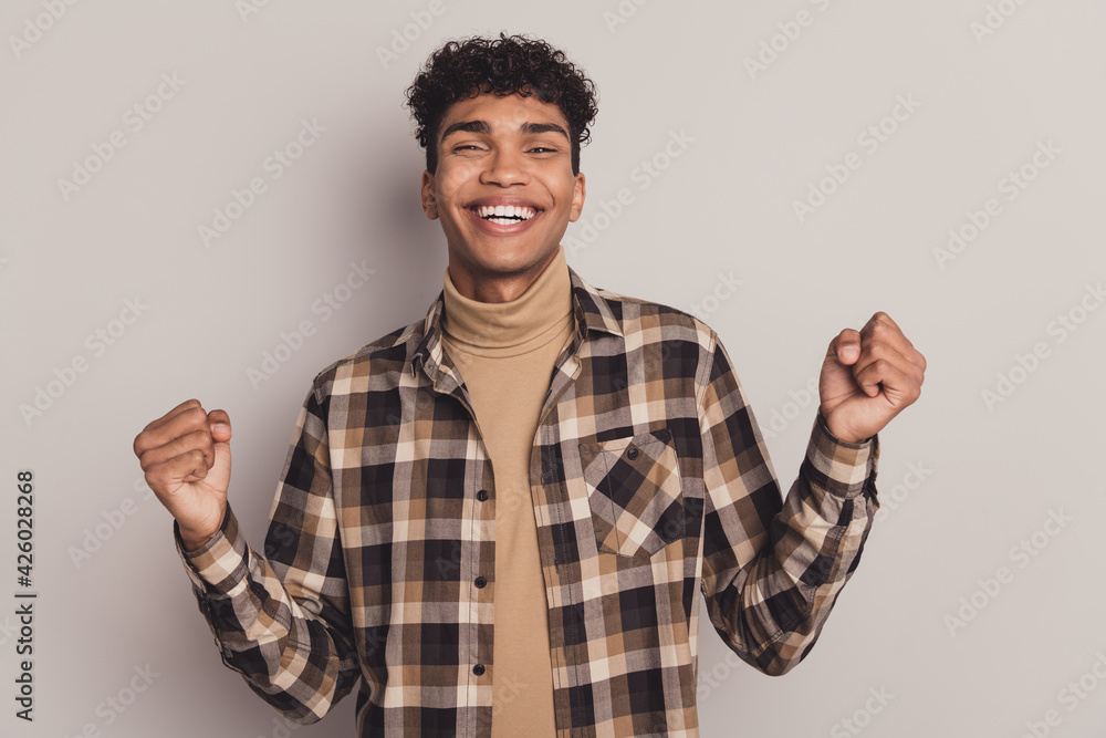 Photo of funny guy raise fists look camera wear checkered shirt turtleneck isolated grey color background Photo of funny guy raise fists look camera wear checkered shirt turtleneck isolated grey color background