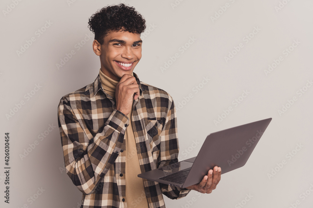 Photo of smart african guy finger chin hold netbook wear checkered shirt isolated grey color background Photo of smart african guy finger chin hold netbook wear checkered shirt isolated grey color background