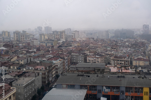 a typical city landscape with factory skyscrapers and a lot of buildings around in a foggy day in winter