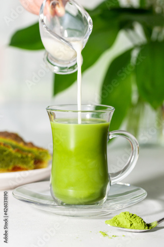 Japanese green tea Matcha in a glass cup with flowing coconut milk.