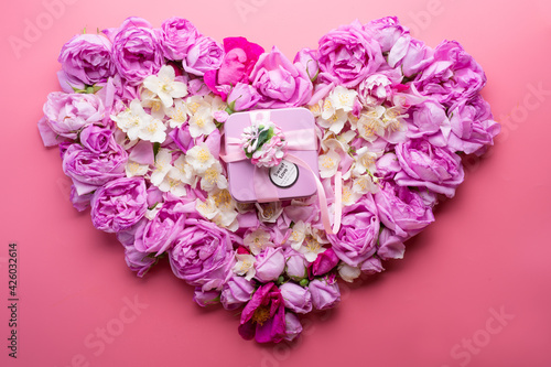 box with gift around roses and jasmine background in heart shape. romantic and beauty concept. top view