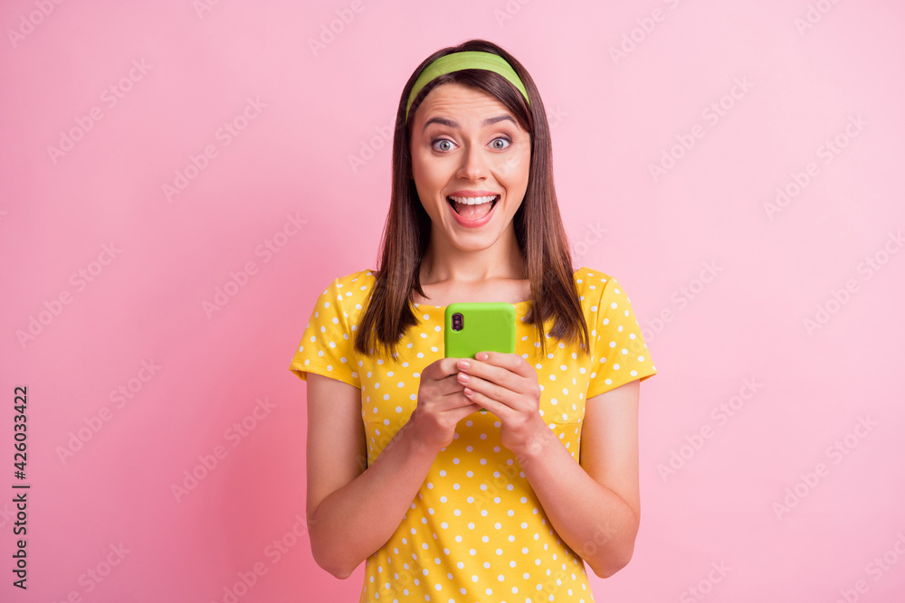 Photo of young attractive smiling cheerful good mood girl with open mouth use cellphone isolated on pink color background Photo of young attractive smiling cheerful good mood girl with open mouth use cellphone isolated on pink color background