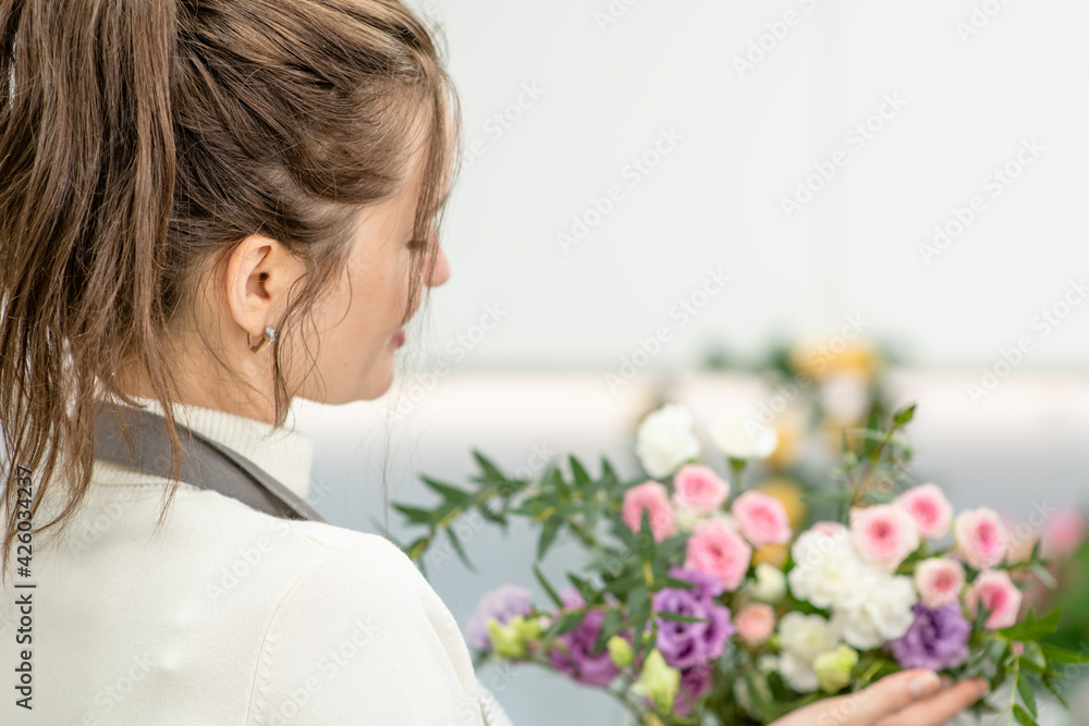 Young woman making fashion bouquet of different flowers inside her floral shop Young woman making fashion bouquet of different flowers inside her floral shop