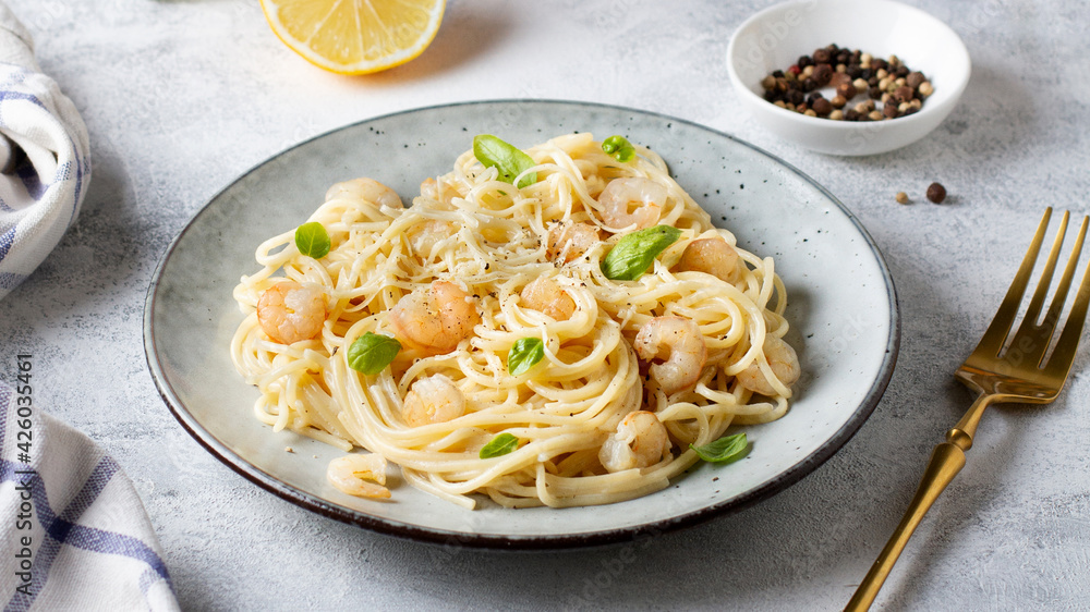 Spaghetti with shrimps and creamy sauce on a gray plate, pasta with seafood.