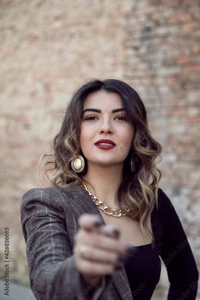 Naklejka premium Close-up front portrait of a cheerful young woman with makeup and hairstyle, stretch out one's hand on front camera.