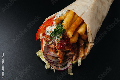 Greek gyros wrapped in pita breads on black background. Gyro pita, shawarma, take away, street food