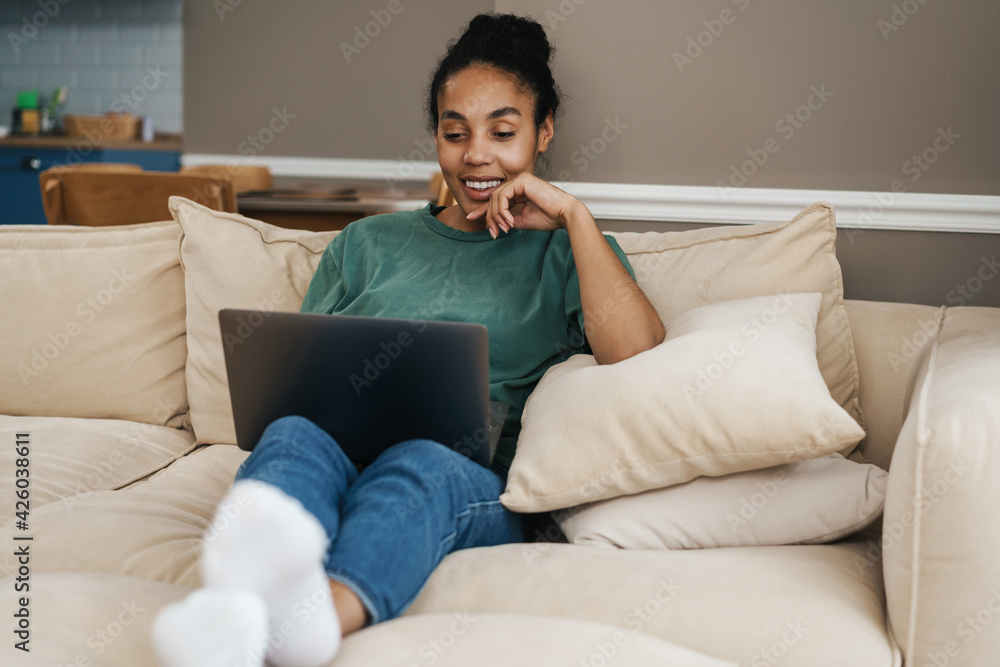 Smiling mid aged african woman sitting on couch Smiling mid aged african woman sitting on couch