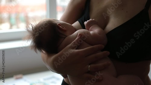 Mom nursing and feeding newborn child in mother's arms. Breastfeeding is an essential way to healthfully nurture and soothe baby. Physical touch and respond to baby's hunger cues. 
