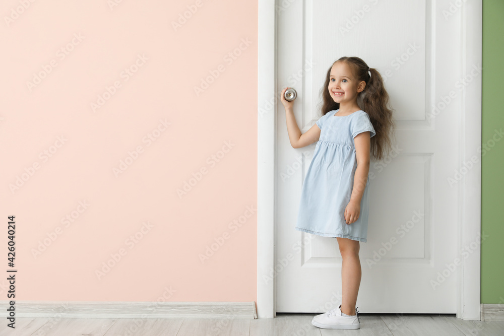 Cute little girl standing near closed door