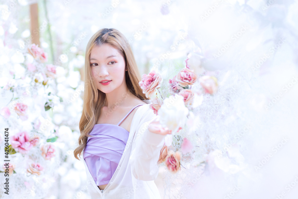 Asian beautiful woman smiles and stands in white rose flower garden as natural , luxury theme