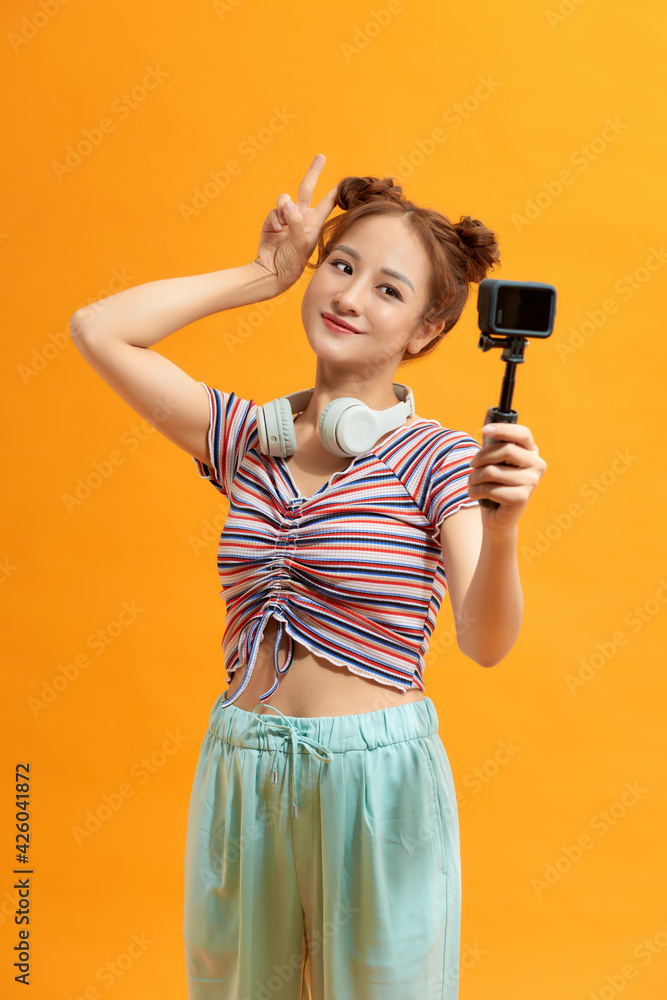 Pretty young woman smiling holding action camera Pretty young woman smiling holding action camera