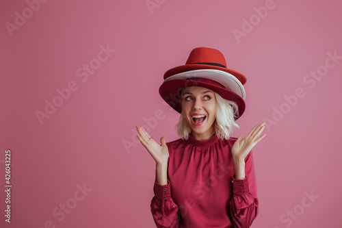 Canvas-taulu Funny, happy smiling fashionable  woman wearing many hats, posing on pink background