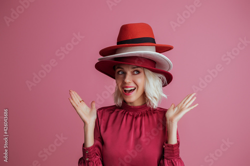 Fototapeta Funny woman wearing many hats  posing on pink background