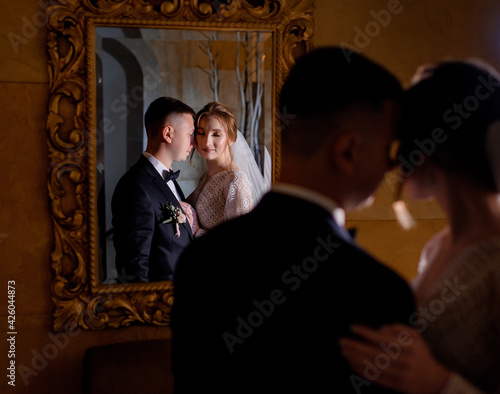 Side view of newlyweds in love hugging in front of a mirror in a hotel room. Concept of wedding day © IVASHstudio