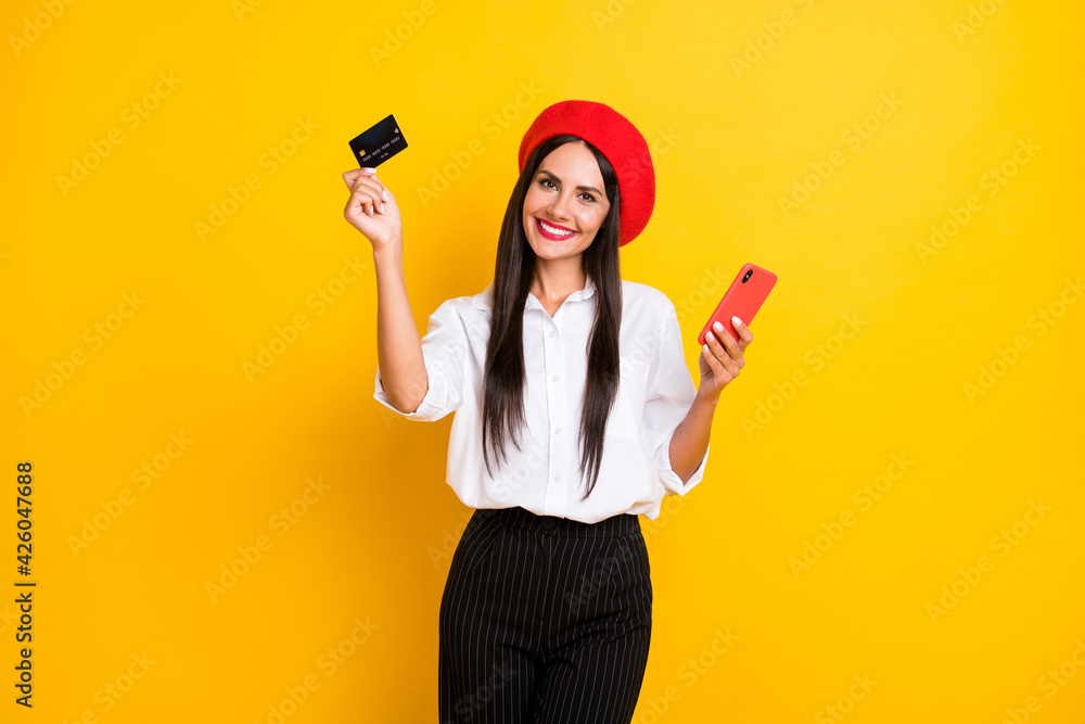 Photo of happy smiling attractive french woman hold credit card purchased phone isolated on yellow color background Photo of happy smiling attractive french woman hold credit card purchased phone isolated on yellow color background