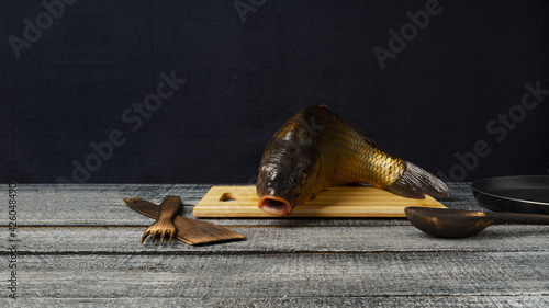 Freshwater fresh raw carp on a cutting board, on a black table. Baner photo