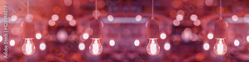 Pendant light concrete gray - light bulbs in concrete socket hang from the ceiling in a living room, with pink red abstract bokeh lights