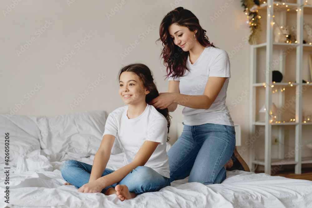 Mother combing hair her cute daughter in bed. Mother combing hair her cute daughter in bed.