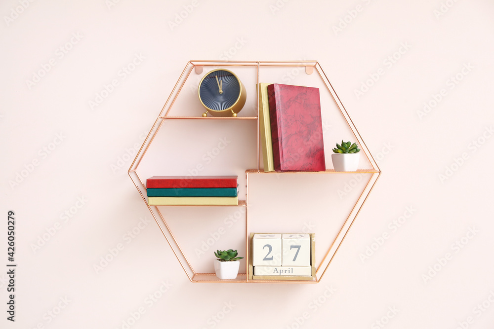 Shelf with books, alarm clock and calendar hanging on color wall Shelf with books, alarm clock and calendar hanging on color wall