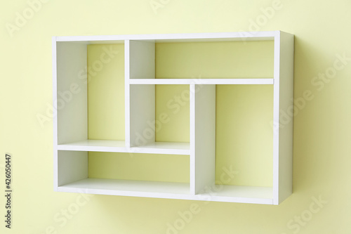 Modern empty shelf hanging on color wall