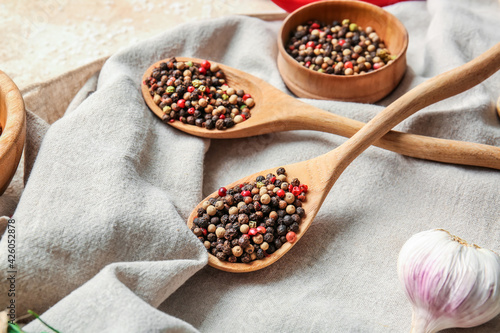 Bowl and spoons with mixed peppercorns on table