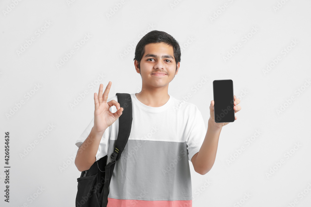 Young indian college student showing smartphone screen on white background. Young indian college student showing smartphone screen on white background.