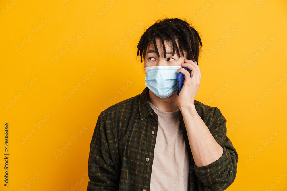Young asian man in face mask talking on mobile phone Young asian man in face mask talking on mobile phone