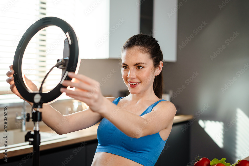 White smiling woman using tripod and cellphone for selfie footage White smiling woman using tripod and cellphone for selfie footage