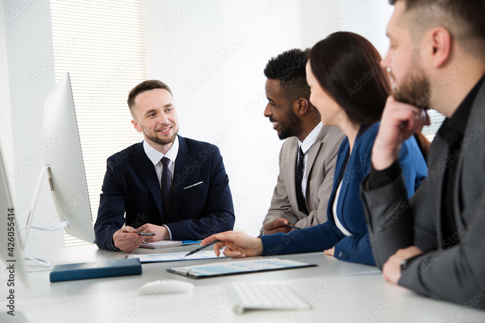 Group of multi-ethnic business people sitting around the office desk and discussing the project Group of multi-ethnic business people sitting around the office desk and discussing the project