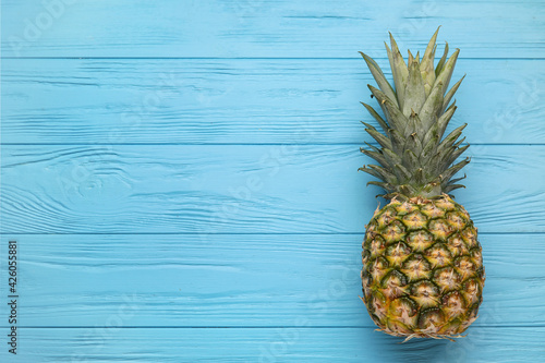 Fresh pineapple on color wooden background