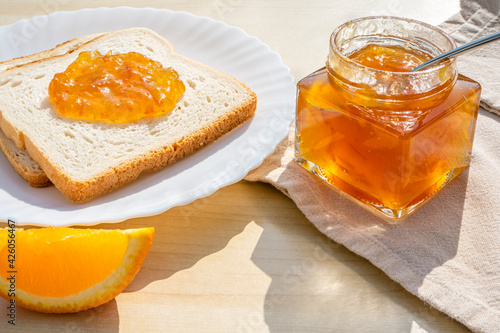 Slices of bread toast with homemade orange jam for breakfast on a wooden background. Breakfast concept