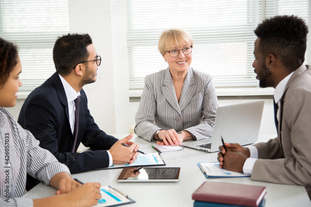 Group of multi-ethnic business people sitting around the office desk and discussing the project Group of multi-ethnic business people sitting around the office desk and discussing the project