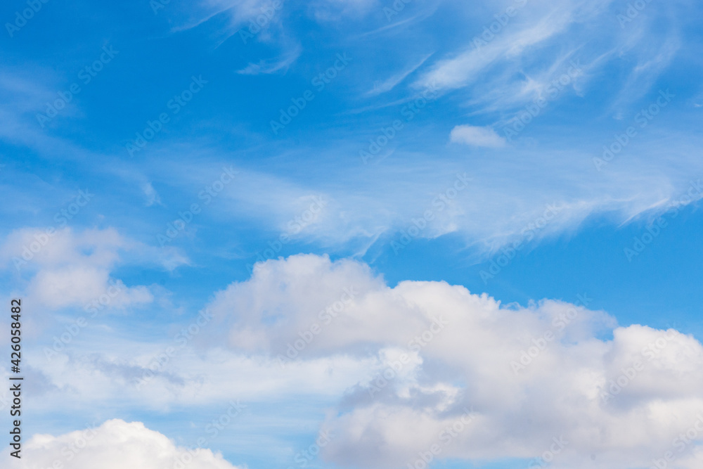 Fluffy white cumulus and cirrus clouds on blue sky in spring Fluffy white cumulus and cirrus clouds on blue sky in spring