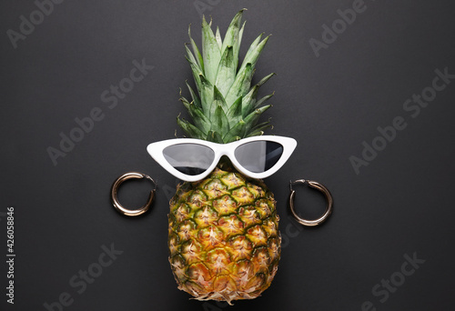 Pineapple with female accessories on dark background