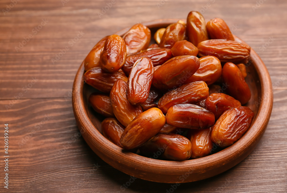 Obraz premium Plate with sweet dried dates on wooden background, closeup