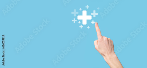 Male hand holding plus icon on blue background. Plus sign virtual means to offer positive thing like benefits, personal development, social network Profit,health insurance, growth concepts photo