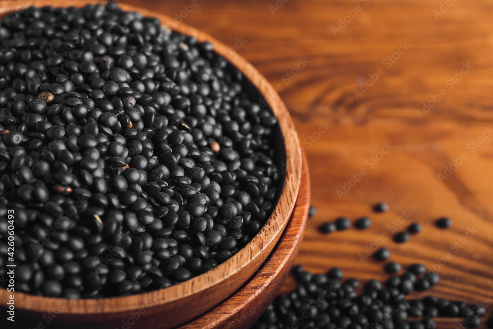 Bowl with black lentils on wooden background Bowl with black lentils on wooden background