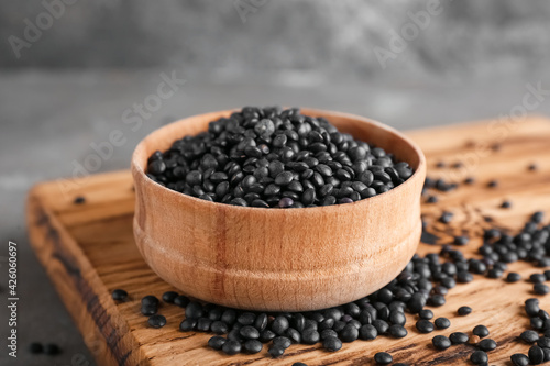 Bowl with black lentils on grunge background