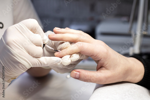 Manicure coating of nails on women's hands with gel polish in a beauty salon by a specialist. Close-up. Space for text
