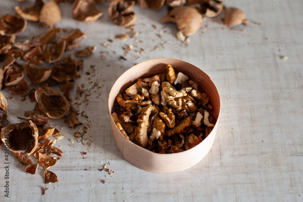 large horizontal photo. Walnut. Peeled walnut grains in an eco-friendly wooden jar. Dry shell. Harvest of nuts. White table. Vitamins. Healthy eating. ECO. large horizontal photo. Walnut. Peeled walnut grains in an eco-friendly wooden jar. Dry shell. Harvest of nuts. White table. Vitamins. Healthy eating. ECO.