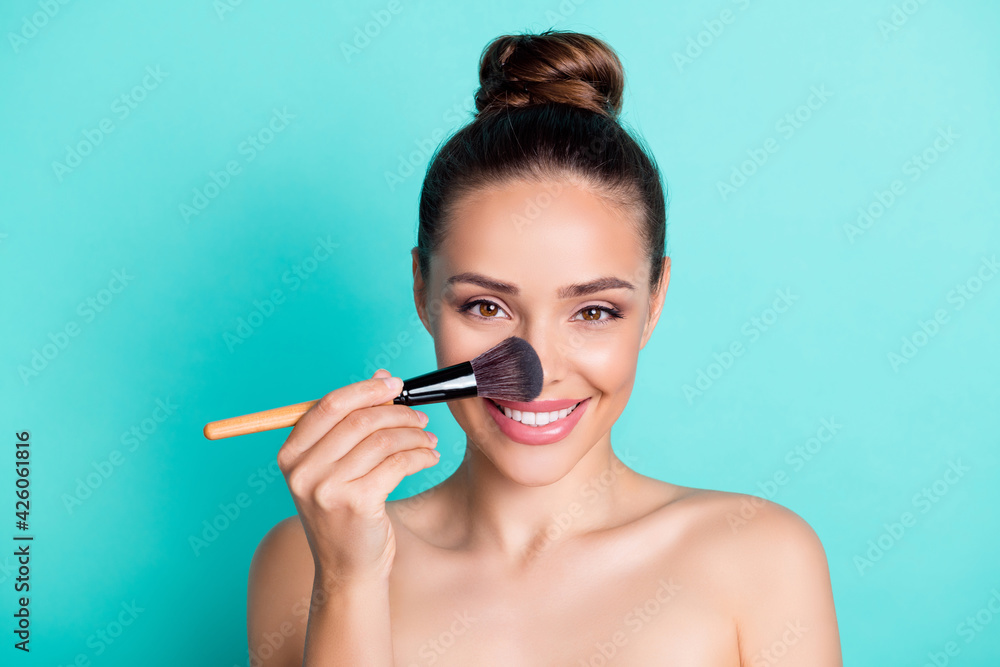Portrait of attractive trendy cheerful girl applying tone cream base highlighter isolated over bright teal turquoise color background Portrait of attractive trendy cheerful girl applying tone cream base highlighter isolated over bright teal turquoise color background