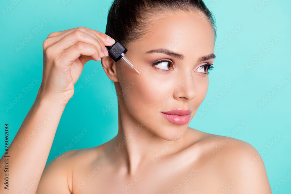 Close-up cropped view portrait of gorgeous trendy girl using oil dropper freshness effect isolated over bright teal turquoise color background Close-up cropped view portrait of gorgeous trendy girl using oil dropper freshness effect isolated over bright teal turquoise color background