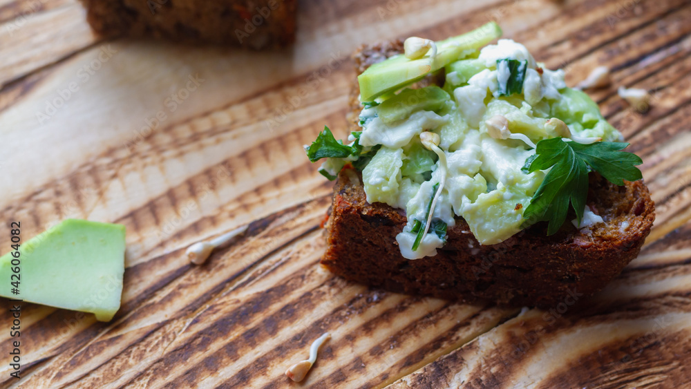 Sandwiches with green sprouted buckwheat, avocado, parsley and rye grain bread on a brown wooden table Sandwiches with green sprouted buckwheat, avocado, parsley and rye grain bread on a brown wooden table