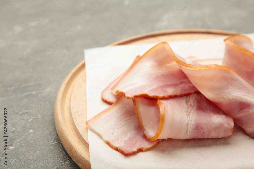 Fresh raw sliced bacon on the wooden cutting board on grey. Fresh raw sliced bacon on the wooden cutting board on grey.
