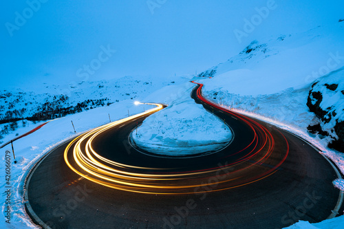 Car trail lights on bends of Bernina Pass road in winter, Val Poschiavo, canton of Graubunden, Engadin, Switzerland photo