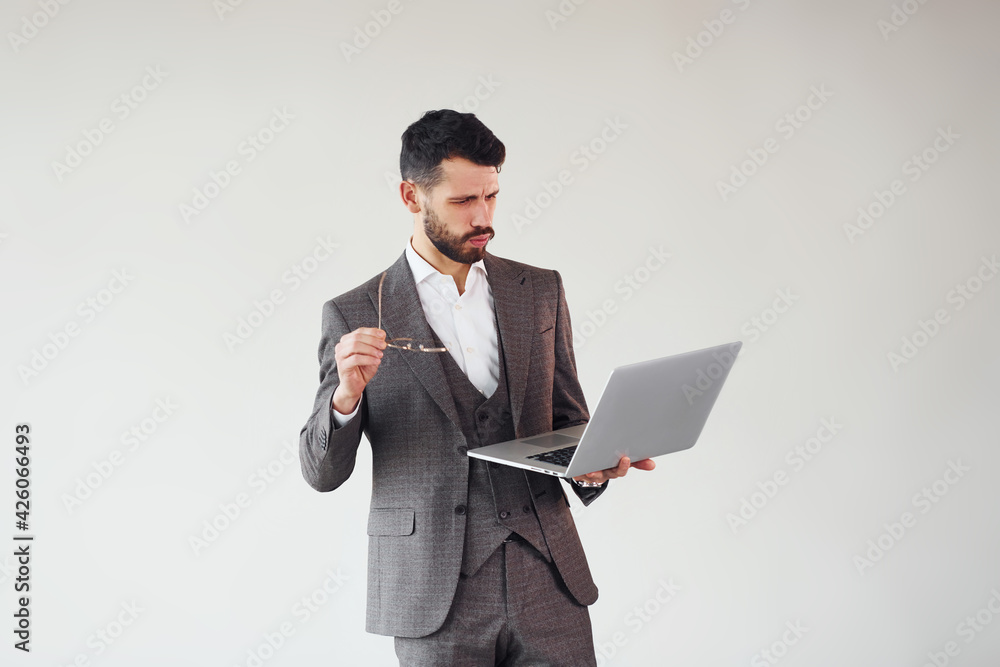 With laptop in hands. Young stylish businessman in suit indoors. Conception of success