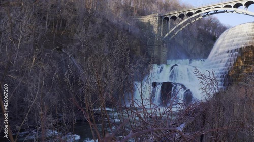 View through dry trees of New Croton dam waterfall. Handheld photo