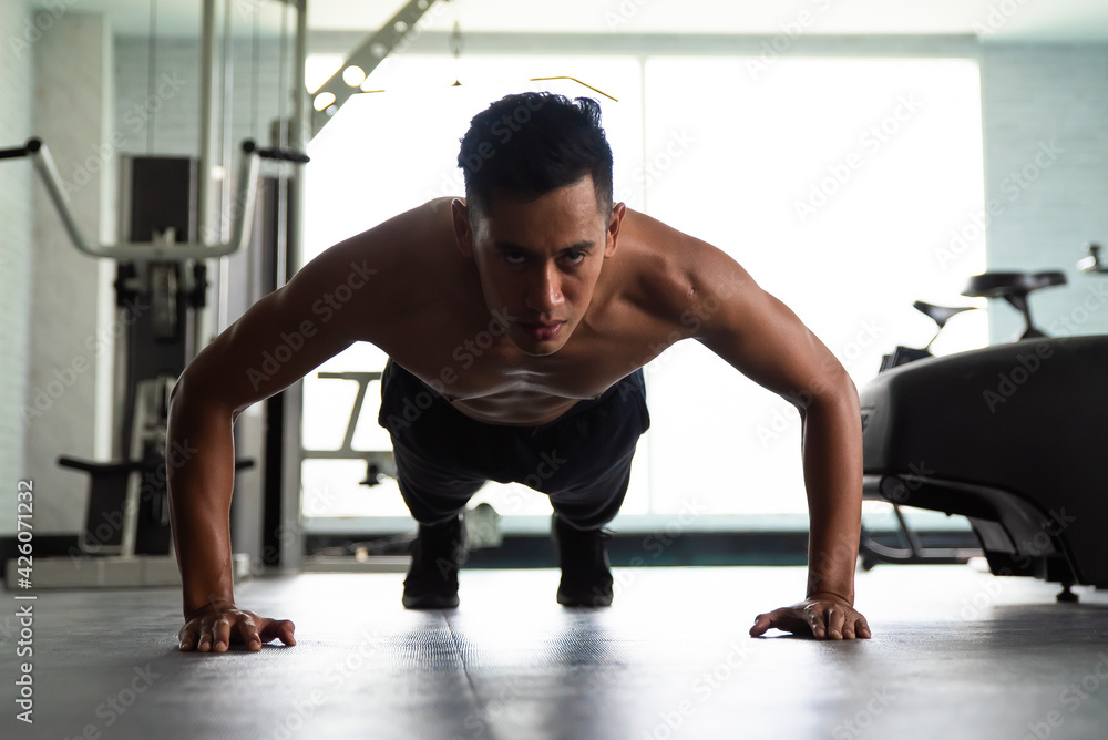 Muscular bodybuilder guy doing push ups in gym. Muscular bodybuilder guy doing push ups in gym.