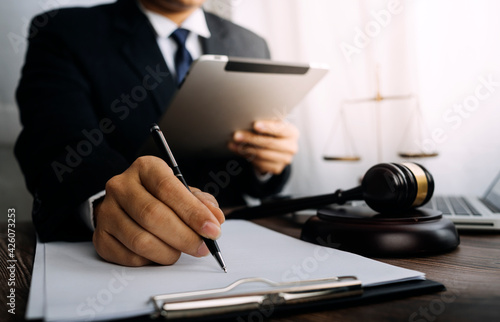 Business and lawyers discussing contract papers with brass scale on desk in office. Law, legal services, advice, justice and law concept picture with film grain effect